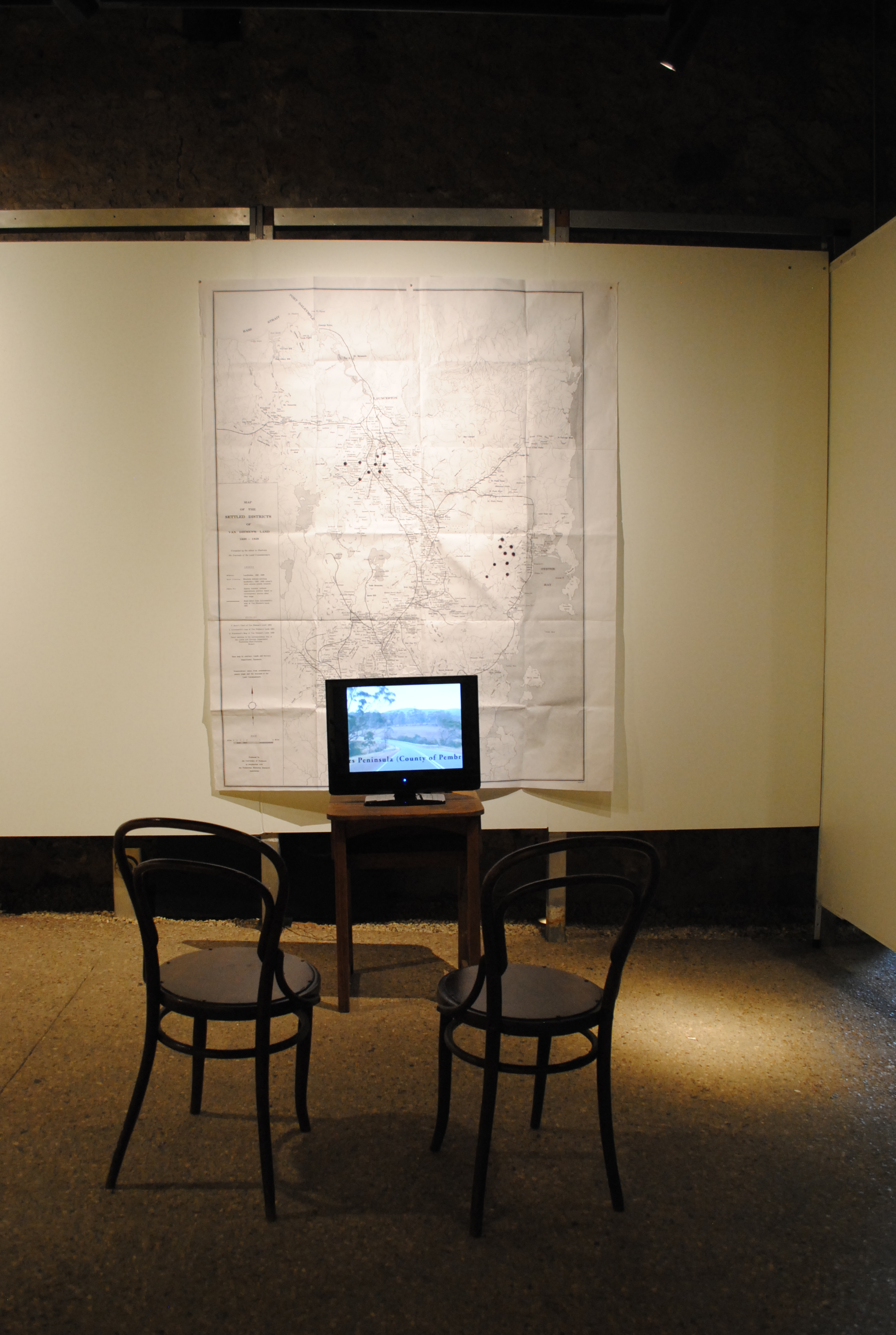 Chairs, table with television monitor playing video, map installed on wall